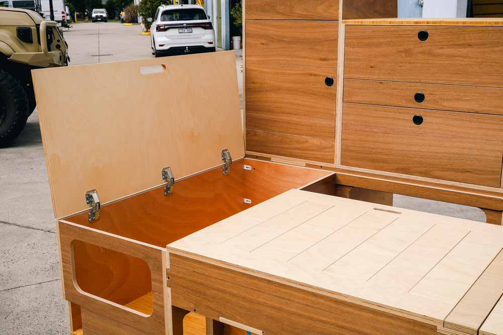 Ply bench with the lid lifted on hidden storage, next to timber-look drawers