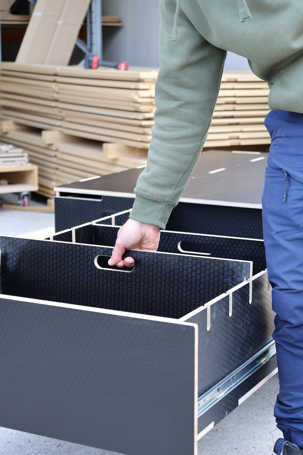 A drawer pulled out on its slides, black panels with a divider inside
