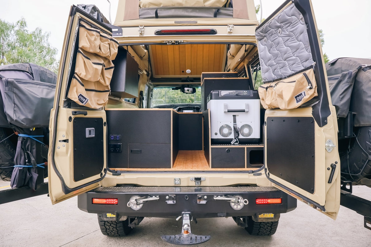 Premium flat pack kit fitted in a Troopcarrier, barn doors open, chest fridge in the rear cabinet