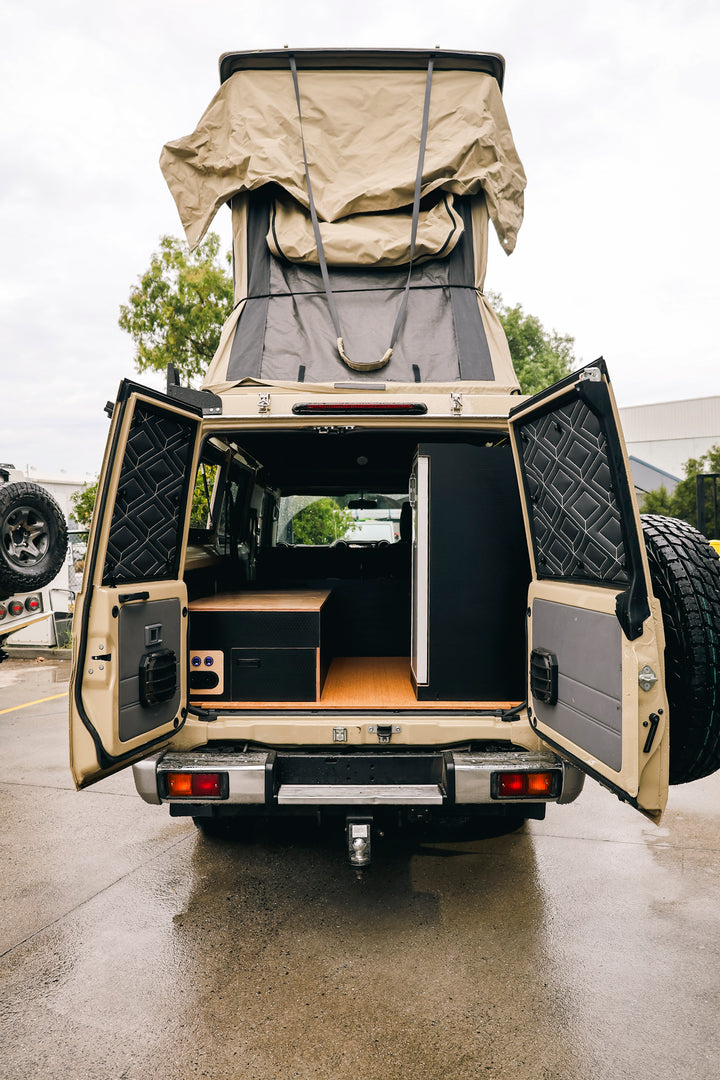 Rear of a sand Troopy with drawers and a fridge fitted