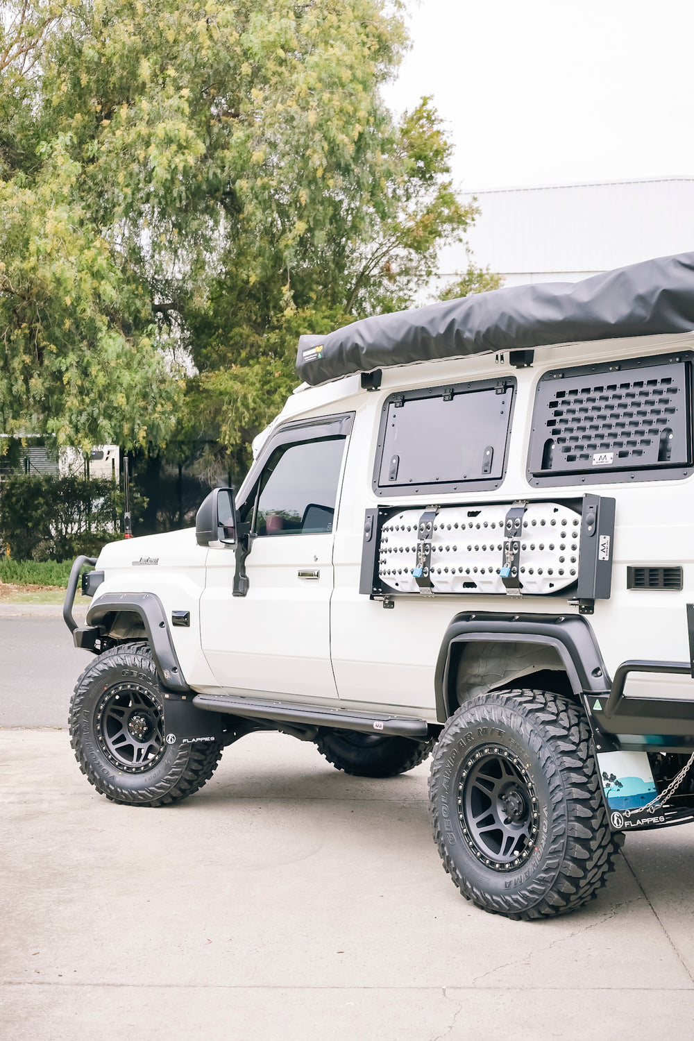 White Troopy with a roof conversion and Maxtrax mounted on the side window